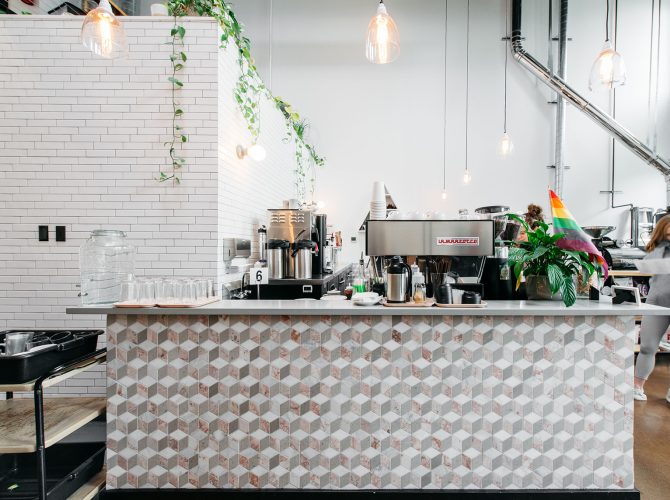 a tiled counter with an espresso machine on top inside of a light and airy cafe