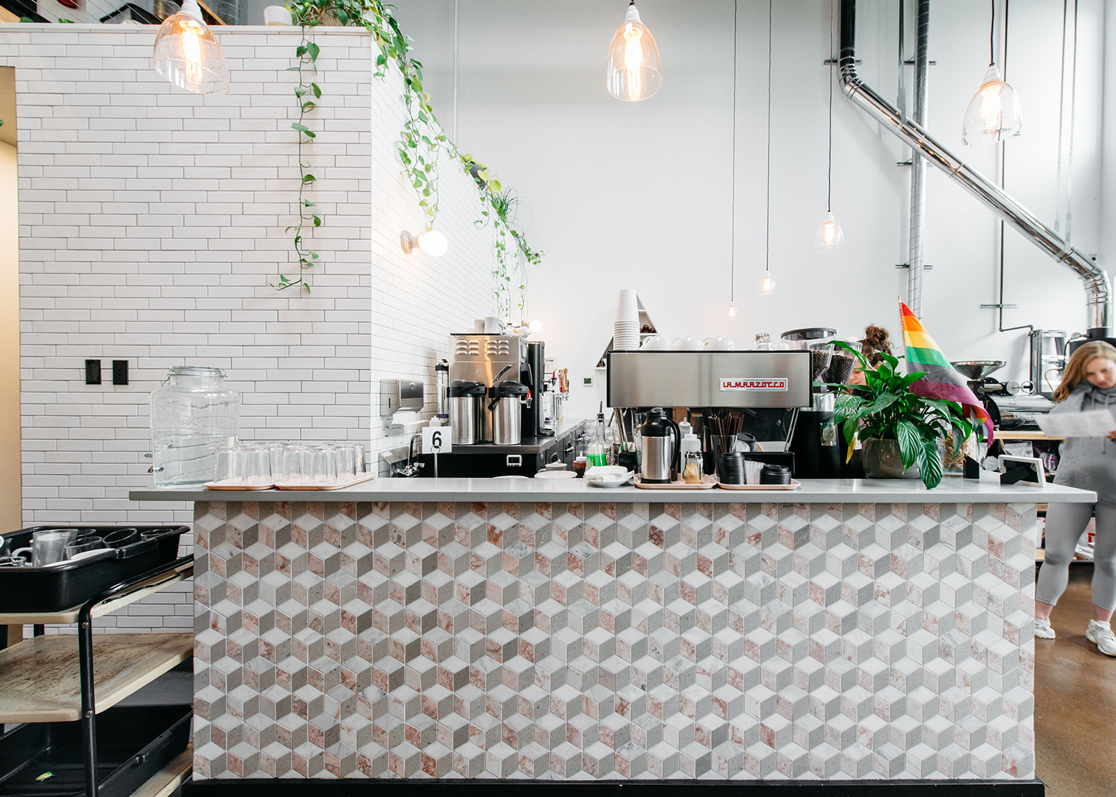 a tiled counter with an espresso machine on top inside of a light and airy cafe