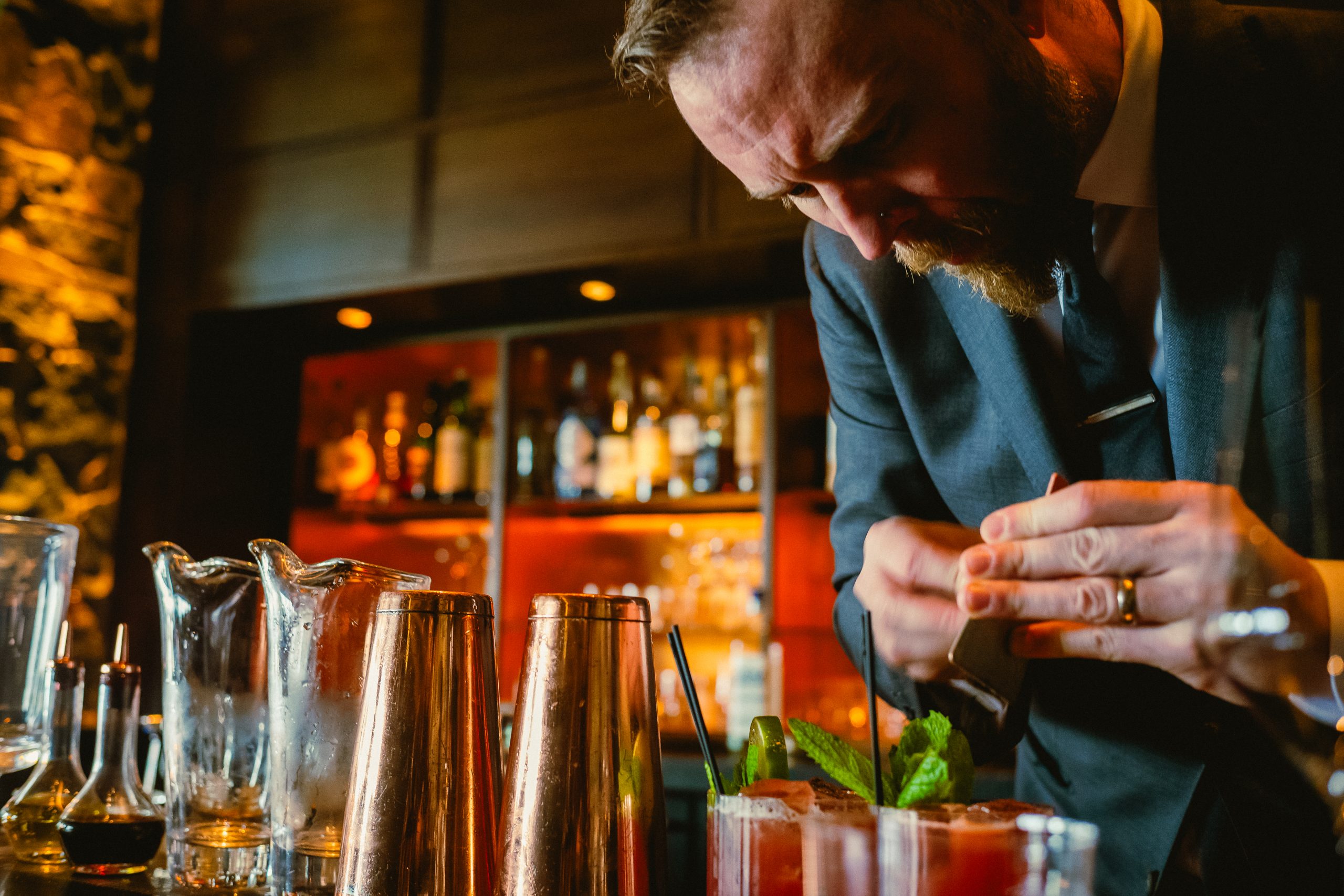 bartender expressing citrus over the top of drinks