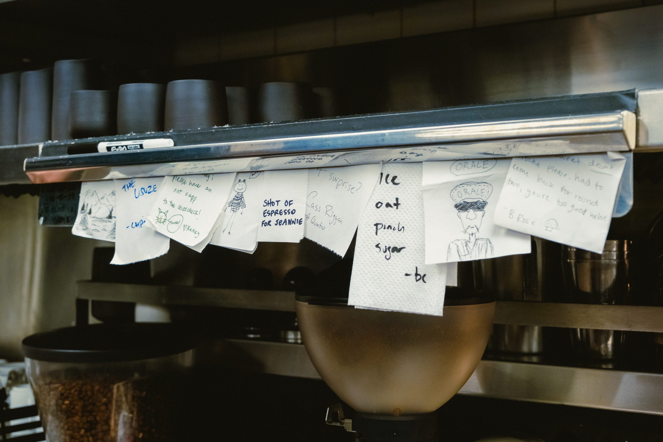 handwritten espresso drink orders for the barista on the ticket rail