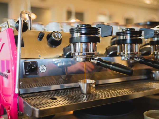 an epsresso shot being pulled on a bottomless portafilter on a pink Strada