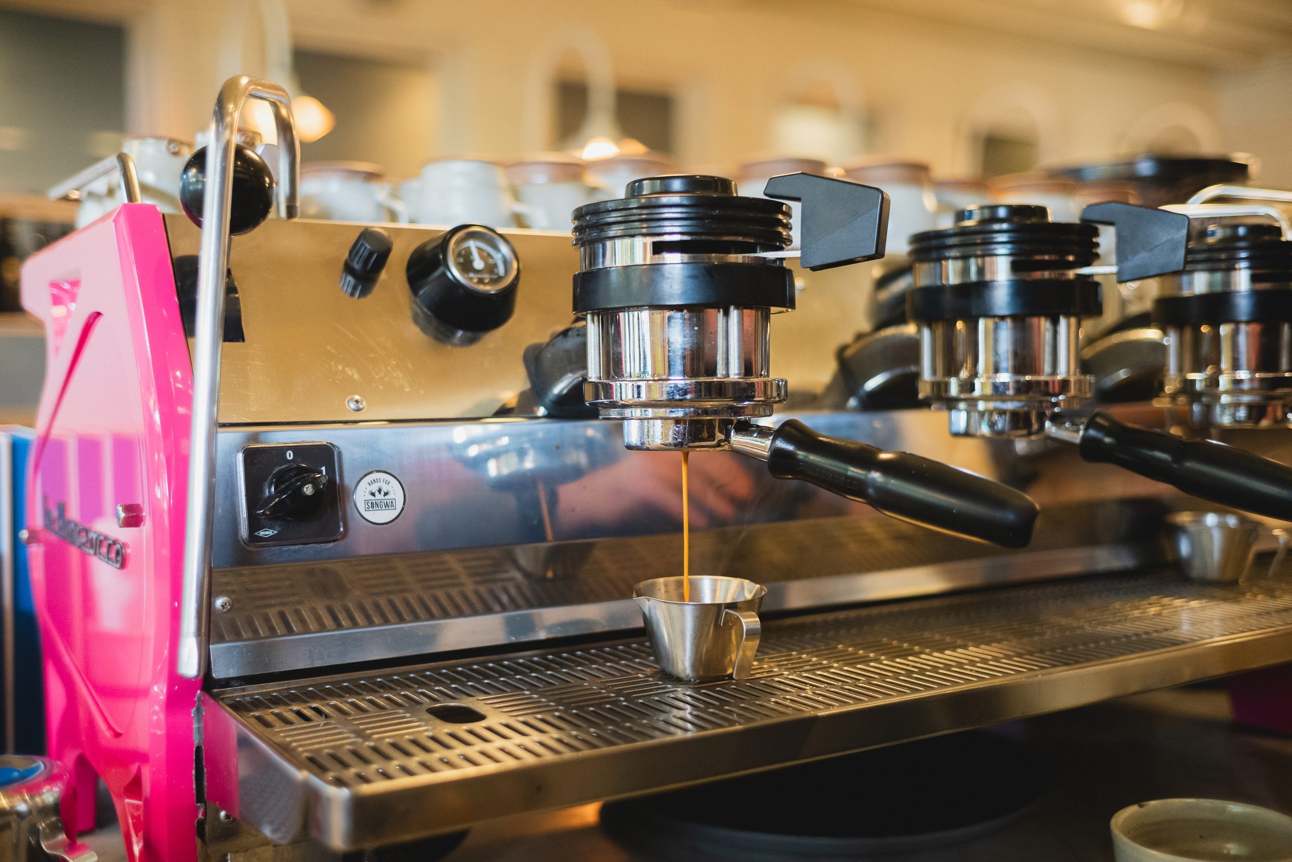 an epsresso shot being pulled on a bottomless portafilter on a pink Strada