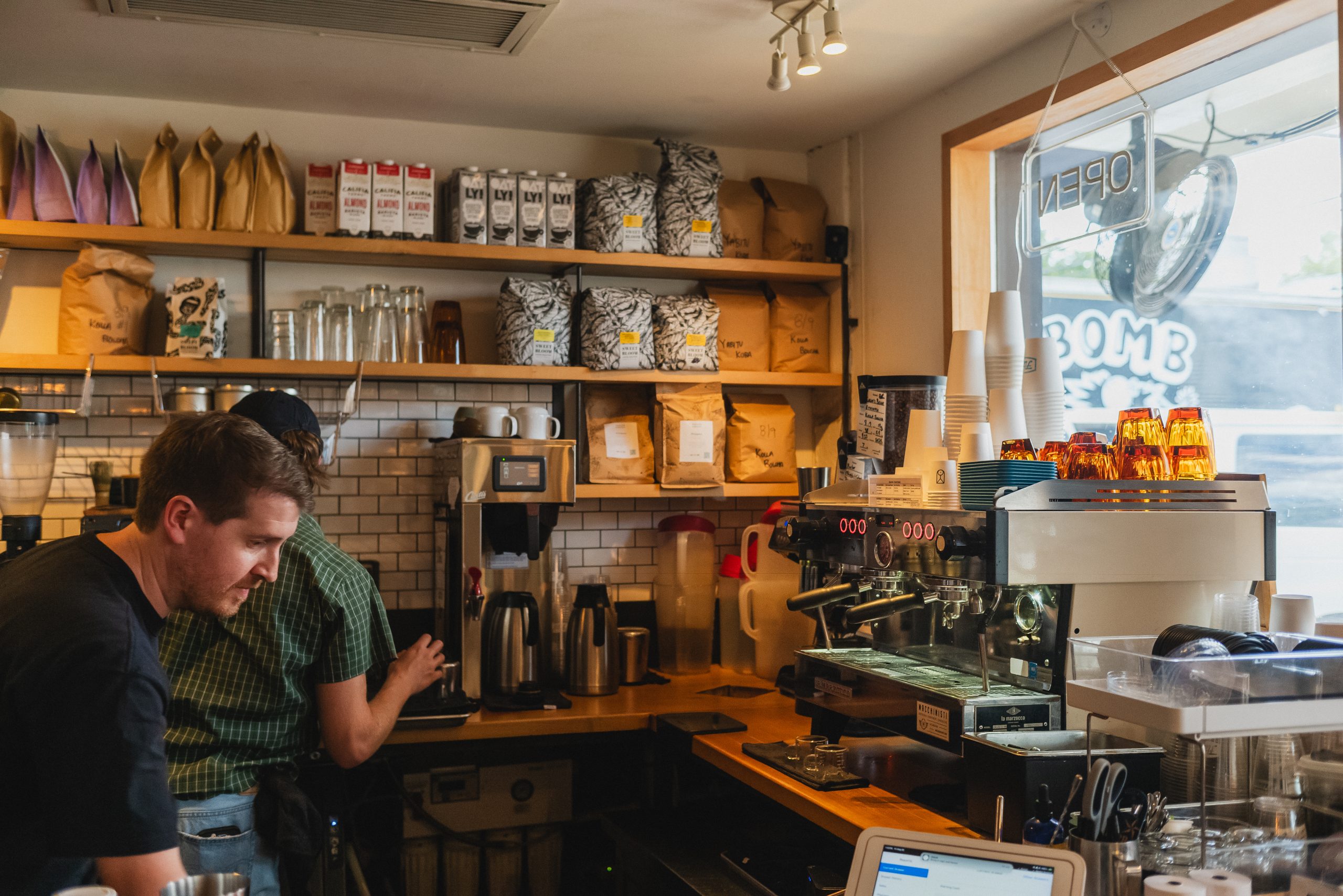 the inside of fleet coffee with two baristas making drinks on a la marzocco linea espresso machine