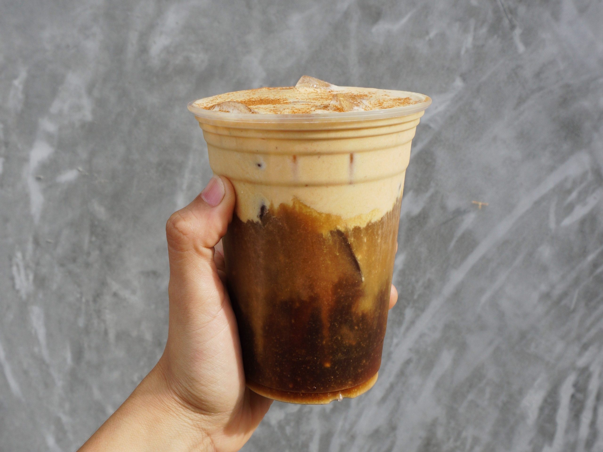 a photo of a hand holding up a pumpkin atole drink