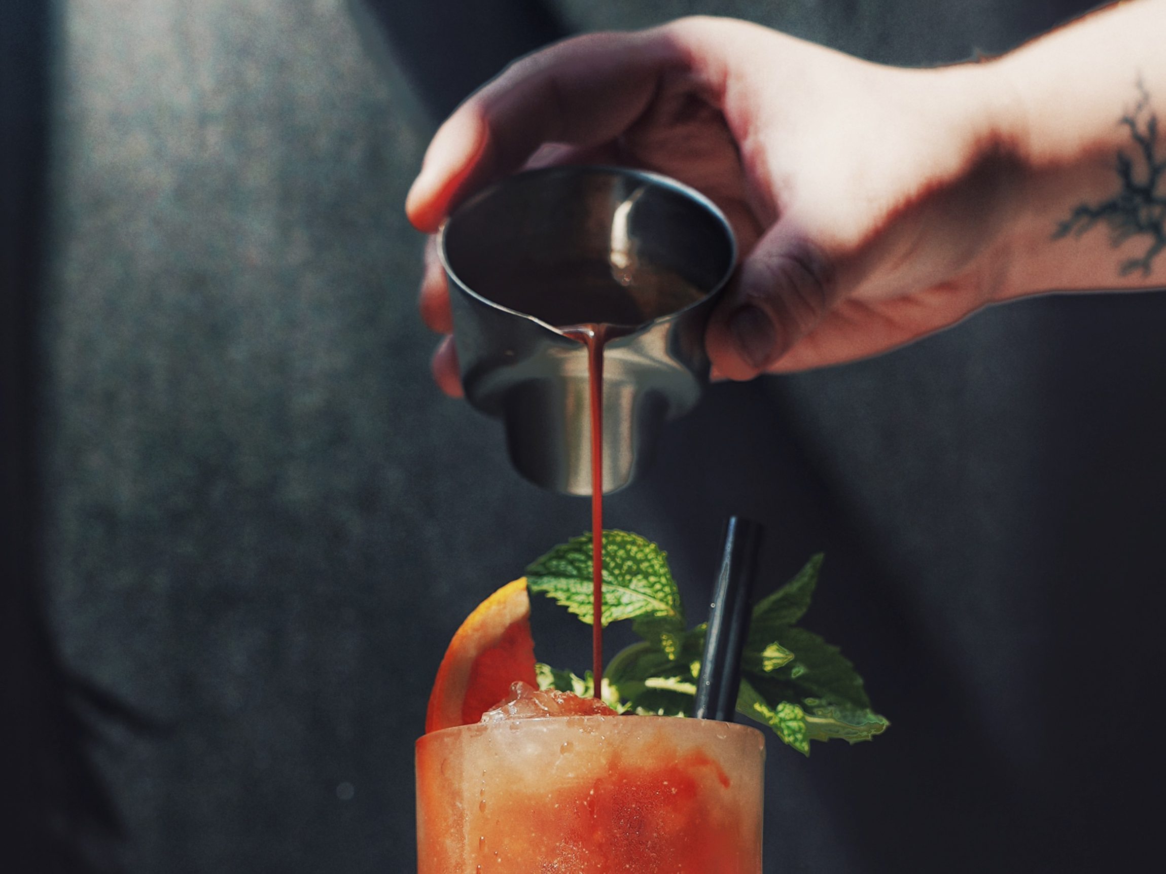 espresso being poured from a metal shot glass onto a tropical looking signature coffee drink