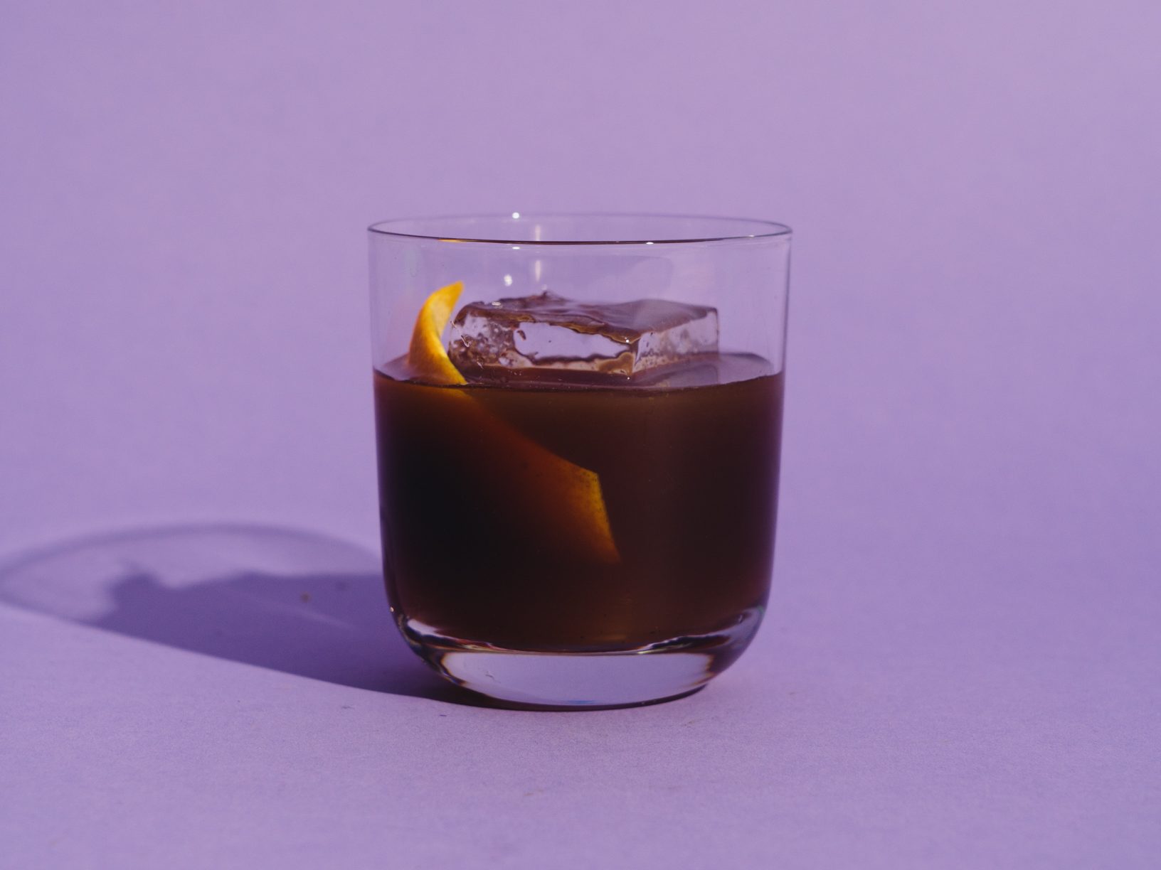 an iced espresso drink with a big clear cube of ice in the center and a citrus garnish