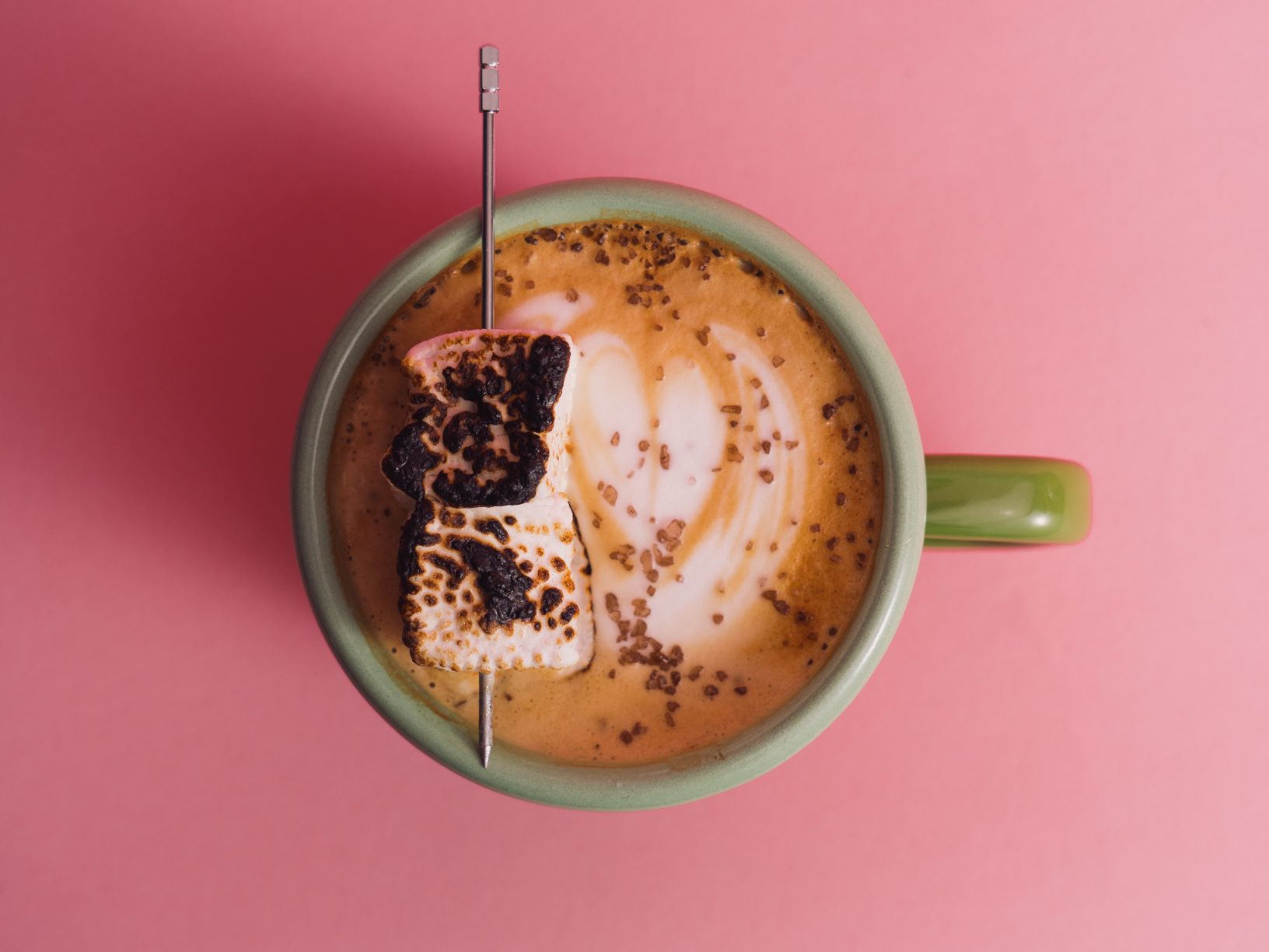 a top view of a specialty latte with a tulip latte art and toasted marshmallows resting on top