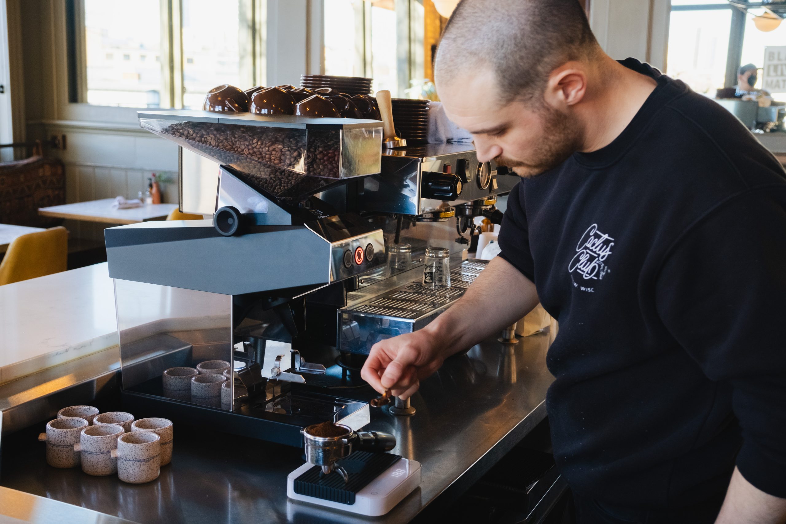 A barista weighing coffee groudn on a La Marocco Swan grinder. 