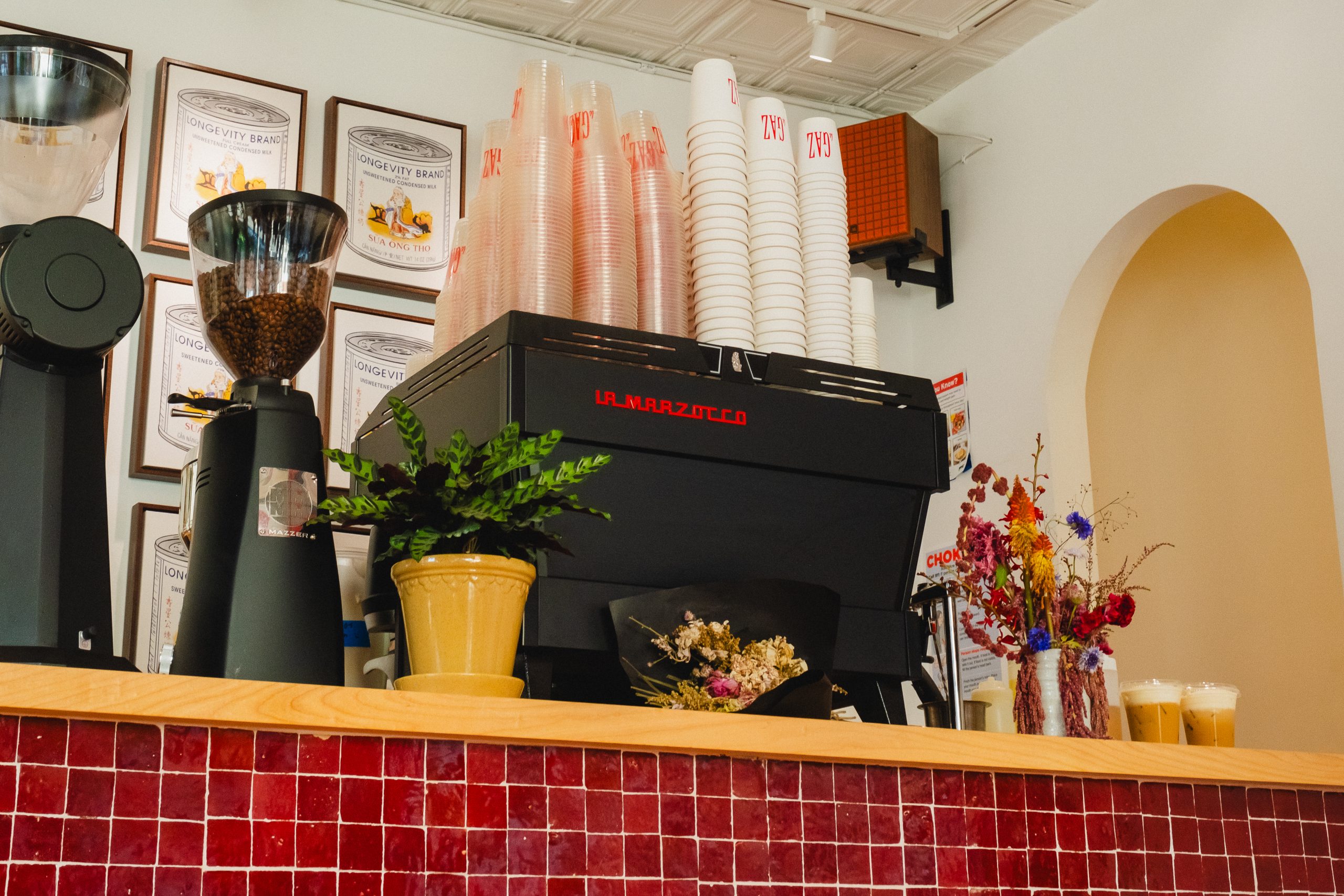 A black Linea PB on a red tile counter in a cafe.