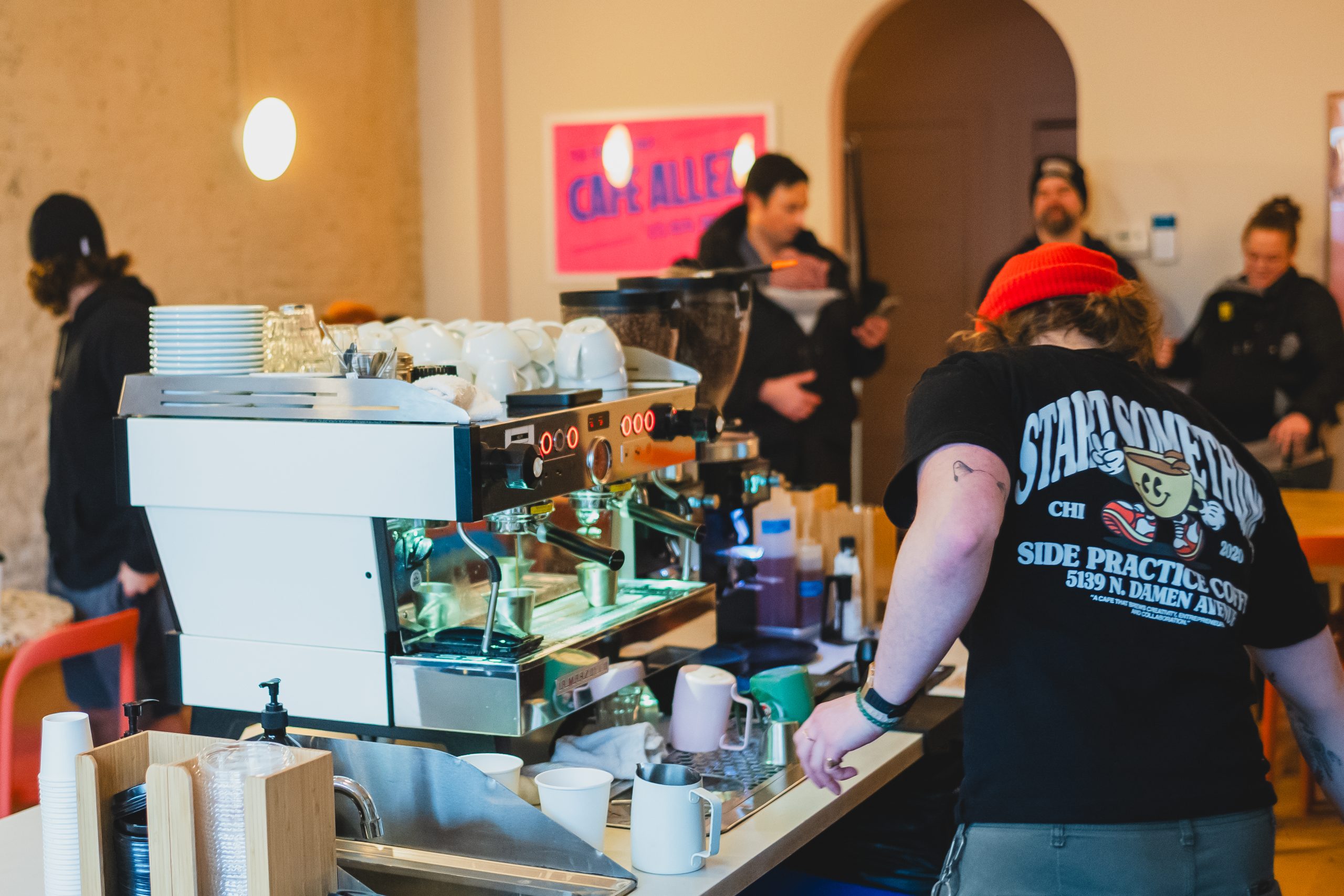 a barista watching shots pull on a Linea PB in a busy cafe. 