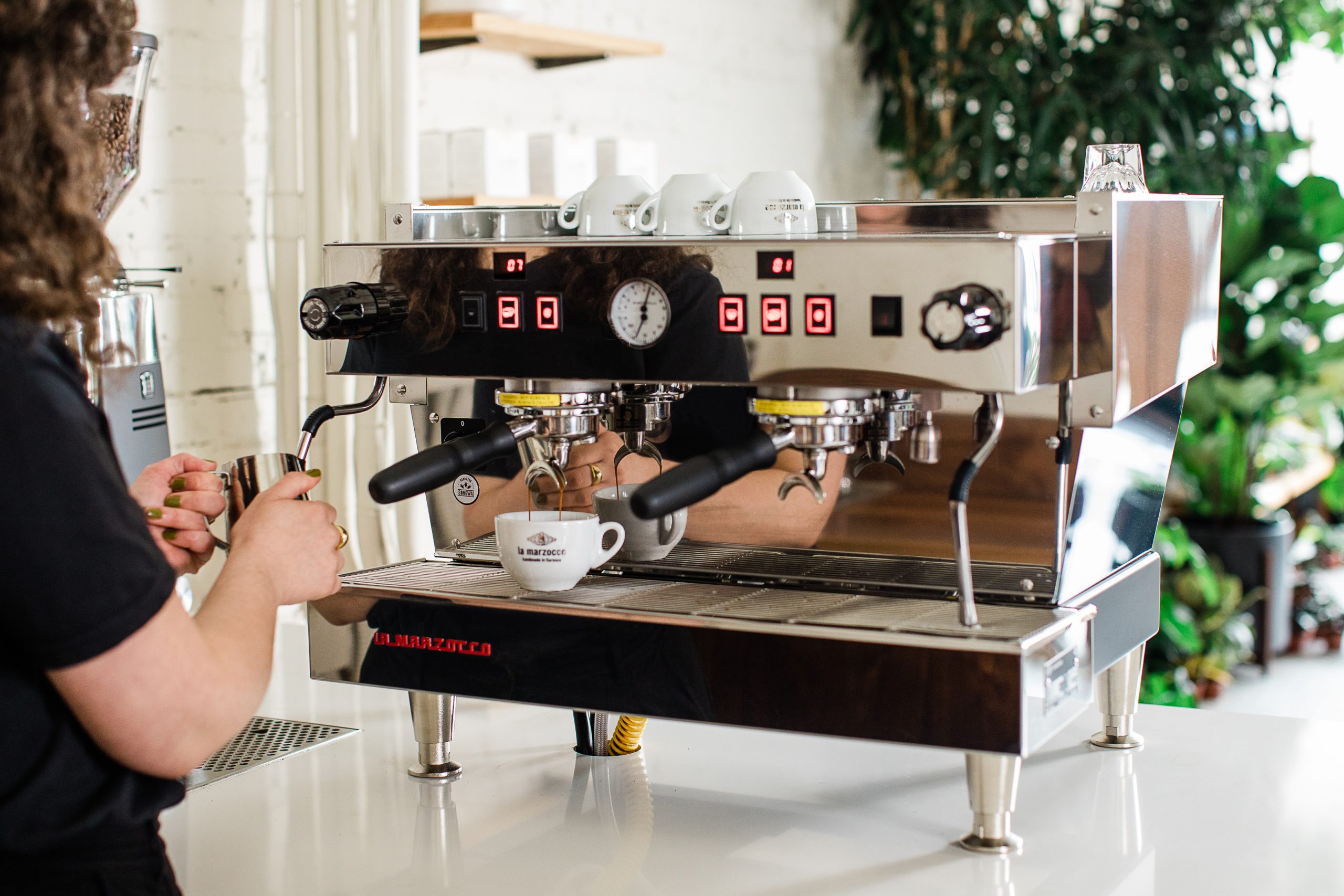 a barista steaming milk while a shot is pulling on a Linea Classic S.