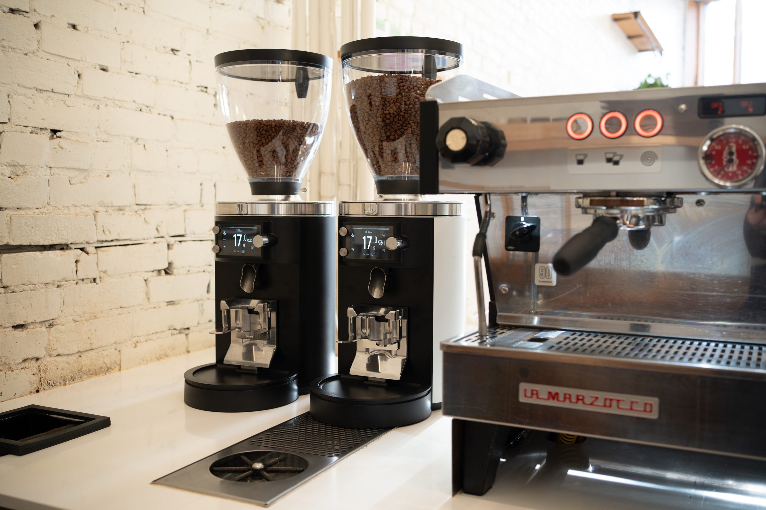 two espresso grinders on a counter next to an espresso machine