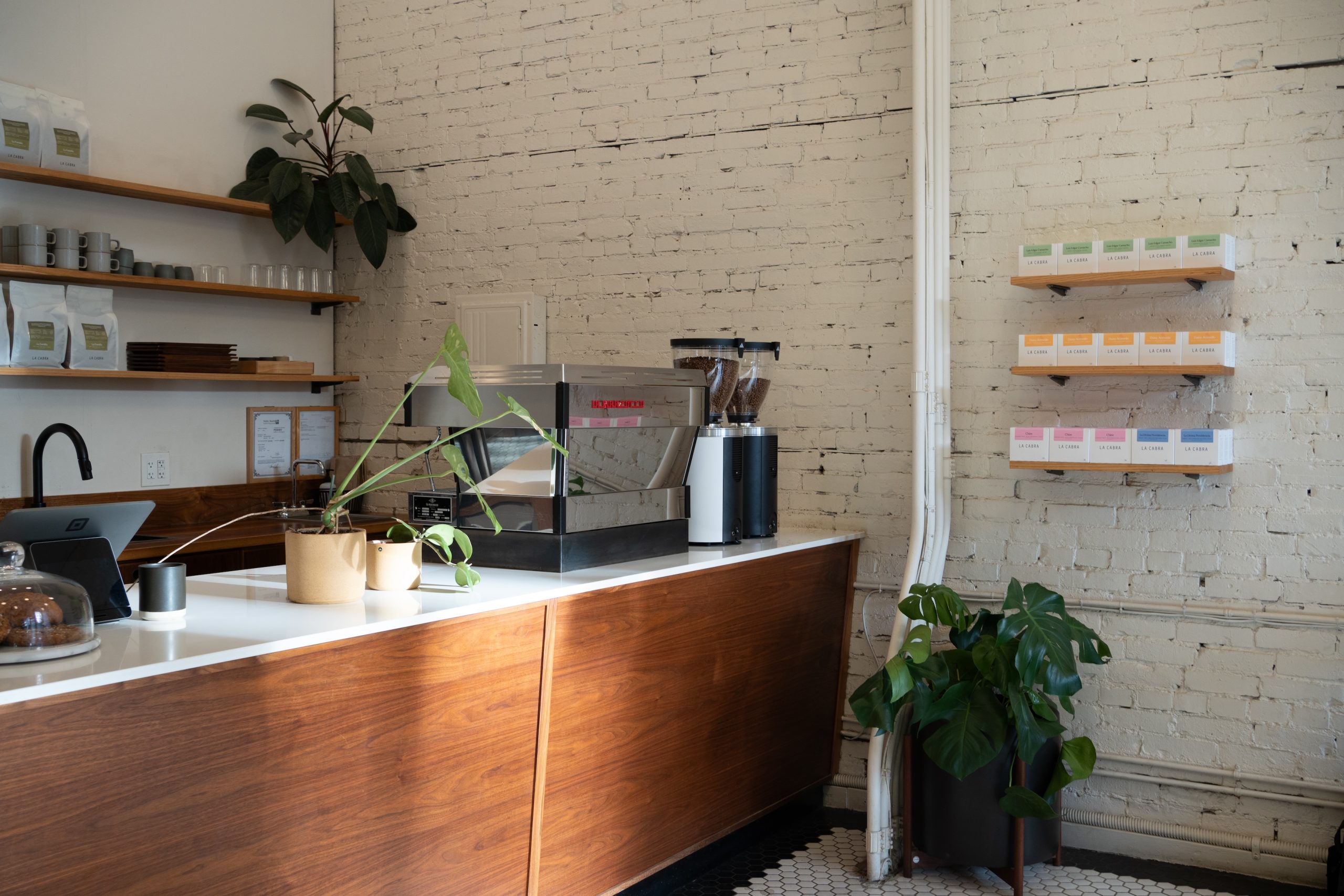 a coffee counter with a la marzocco espresso machine and two grind-by-sync grinders