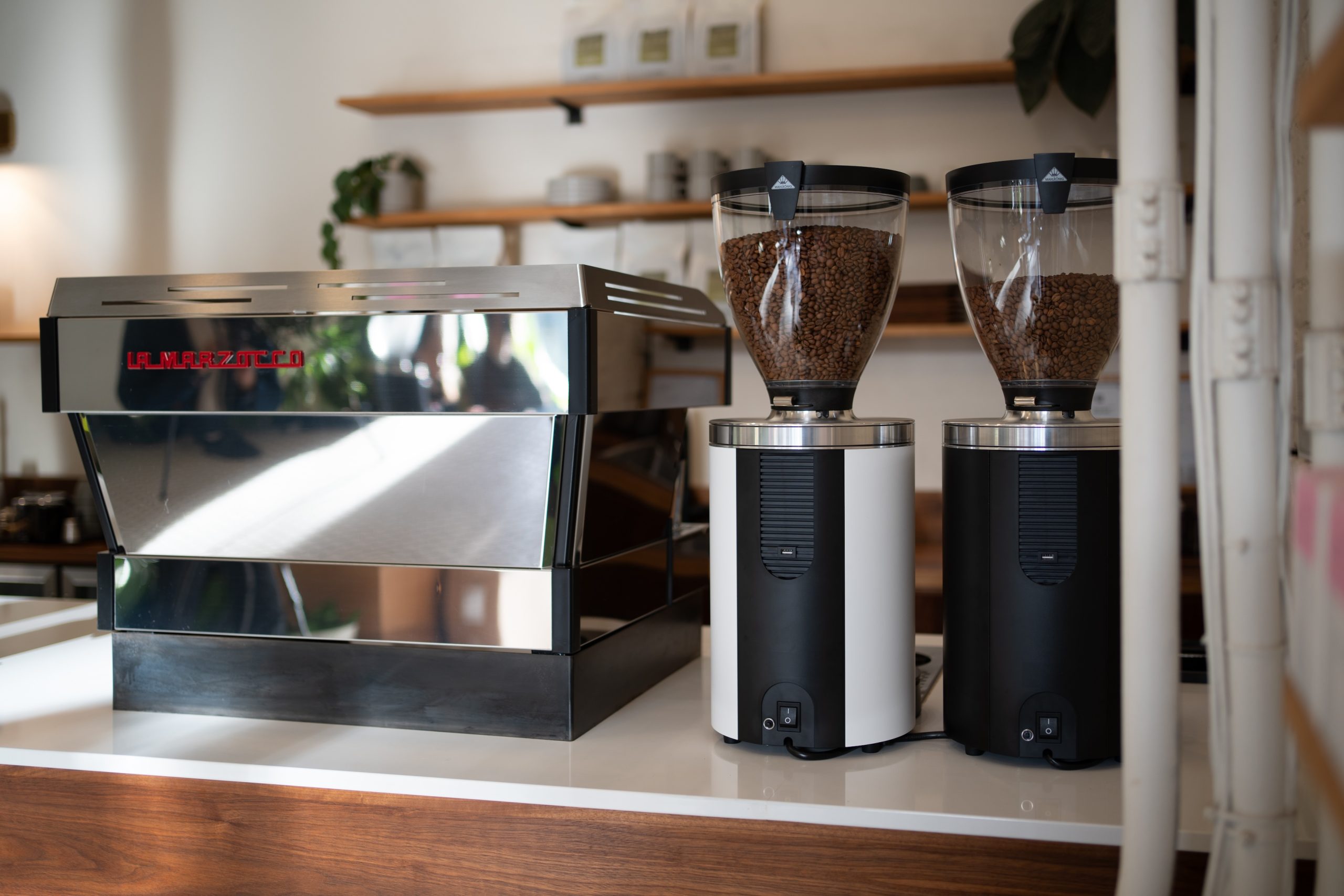 two sync grinders next to an espresso machine on the counter