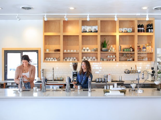 the owners of fiddlehead fern cafe behind the counter of their coffee bar