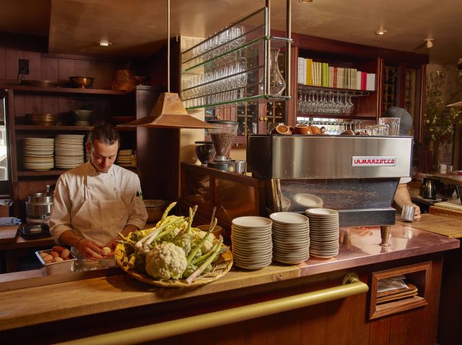 a chef prepping food on a counter next to a la marzocco linea