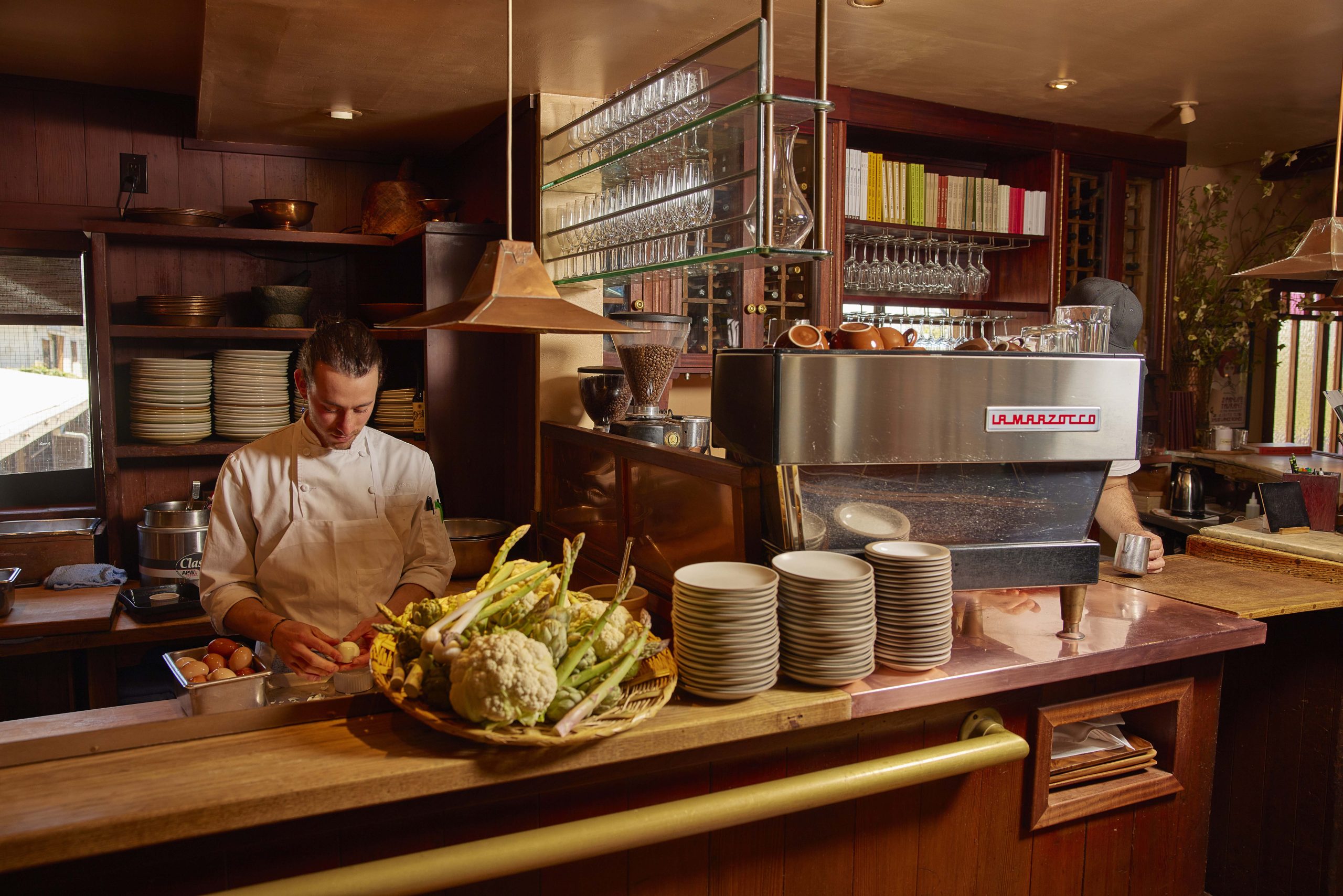 a chef prepping food on a counter next to a la marzocco linea