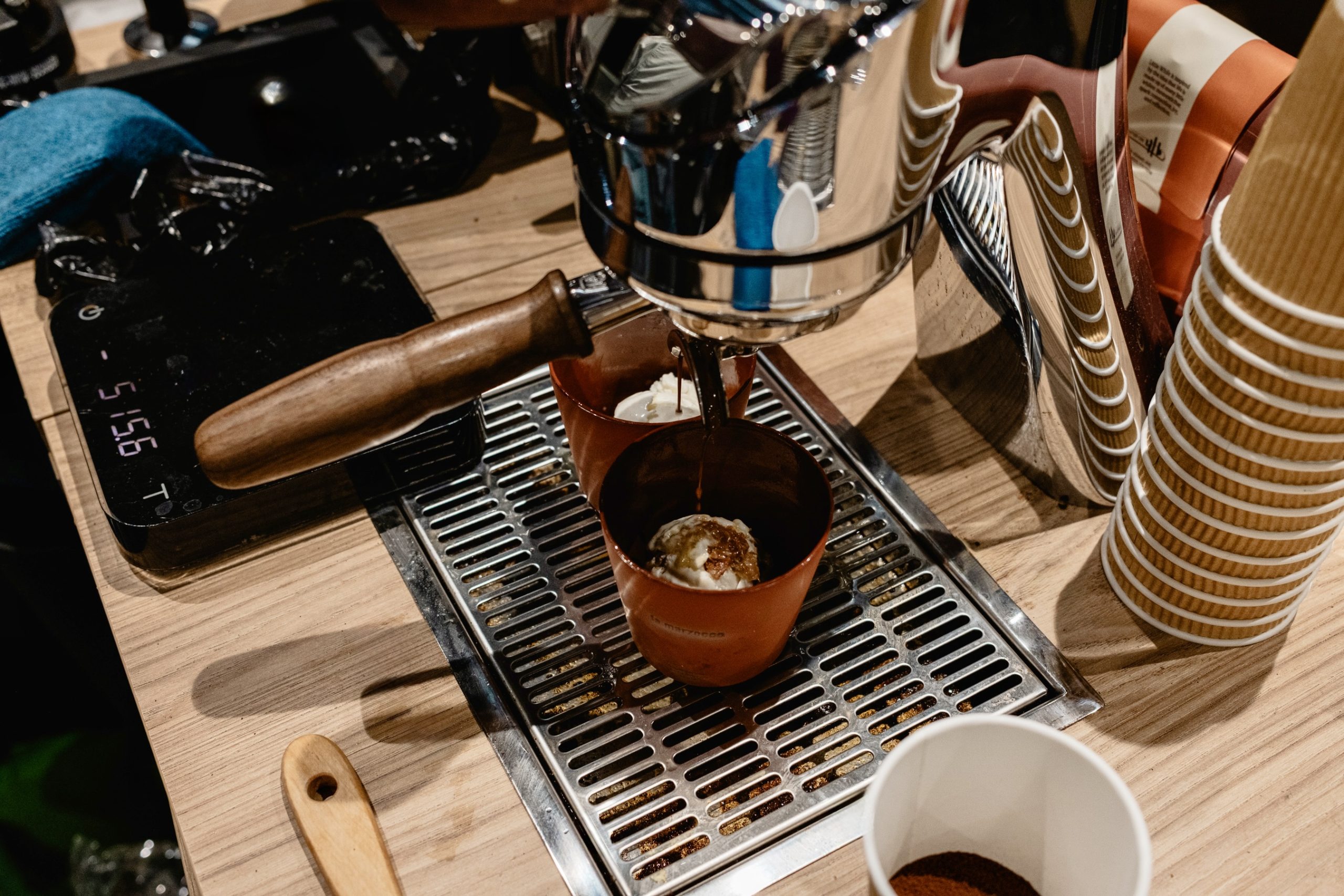 an overhead shot of a modbar brew head pulling espresso over two scoops of ice cream in clay cups at World of Coffee 2026